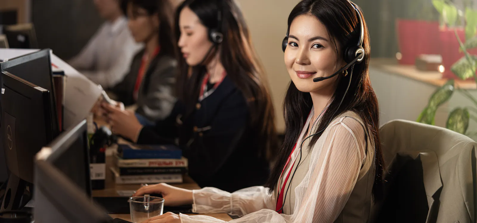A smiling support team member wearing a headset at her desk