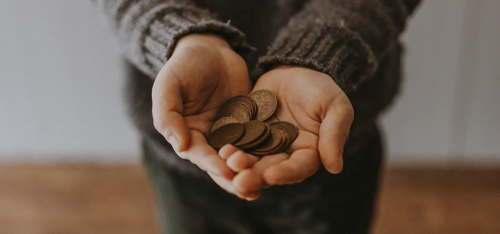 A person holding out a handful of coins in cupped hands