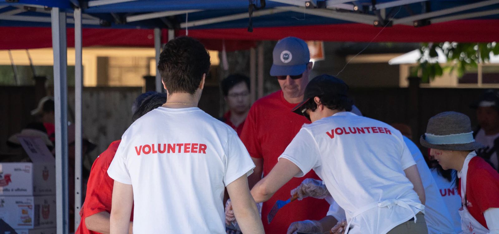 A community group running a fundraising stall together under a tent at an outdoor event