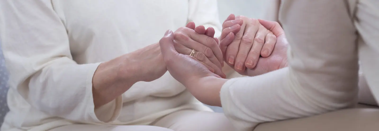 Two people holding hands in compassionate support